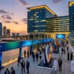 Business professionals gather along the waterfront at Abu Dhabi Global Market during Abu Dhabi Finance Week, with modern office towers, digital finance displays, and the Abu Dhabi skyline at sunset highlighting the city's role as a global financial and investment hub.
