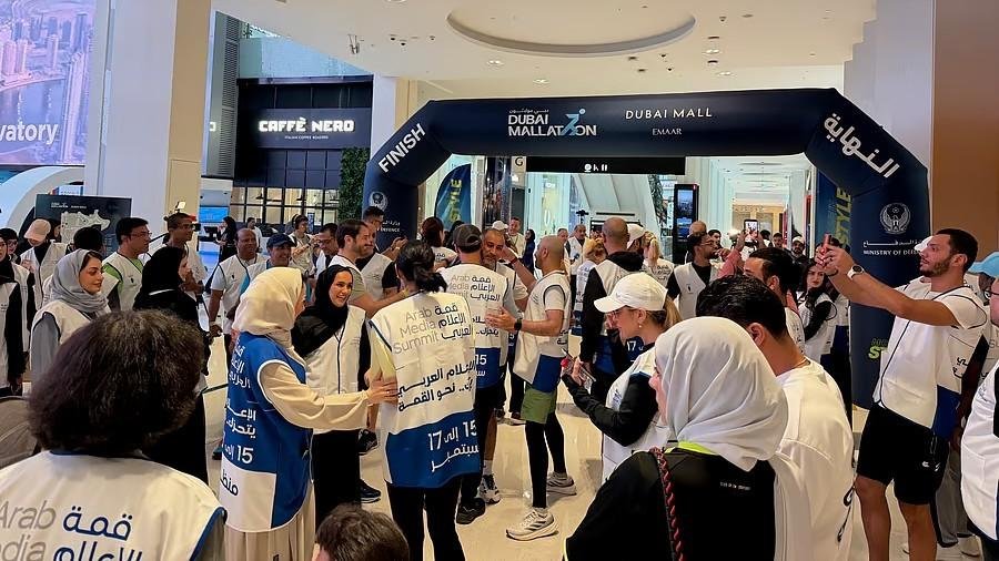 Participants gather beneath the Dubai Mallathon finish arch during the Arab Media Summit 2026 Mallathon, networking and celebrating the opening event at Dubai Mall.