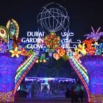 Entrance to Dubai Garden Glow at Zabeel Park featuring colourful illuminated arches, floral decorations, and the park's main entrance sign at night.