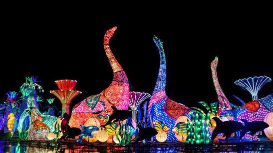 Illuminated dinosaur sculptures at Dubai Garden Glow's Dinosaur Park with colourful LED lighting and themed decorations at night.