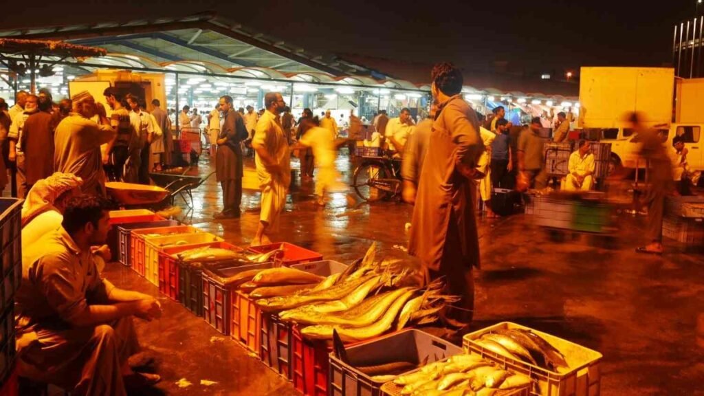The old Deira Fish Market in Dubai at night, showing busy seafood traders, fresh fish in crates, and the lively open air market before it was replaced by the Waterfront Market in 2017.