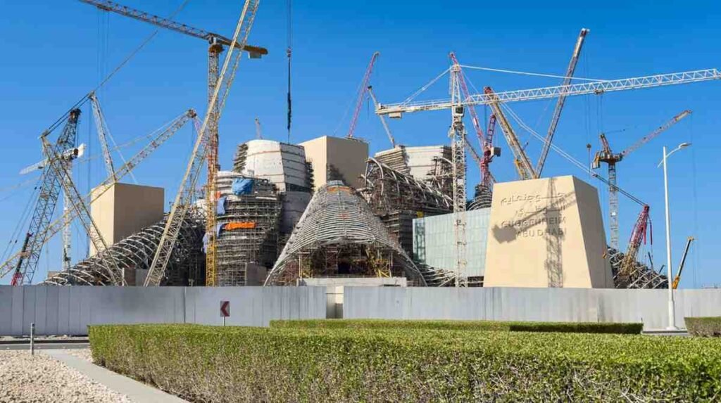 Construction of the Guggenheim Abu Dhabi on Saadiyat Island, showing Frank Gehry's distinctive cone shaped structures surrounded by cranes and scaffolding as the museum nears completion.