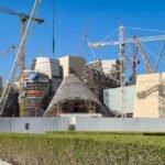 Construction of the Guggenheim Abu Dhabi on Saadiyat Island, showing Frank Gehry's distinctive cone shaped structures surrounded by cranes and scaffolding as the museum nears completion.