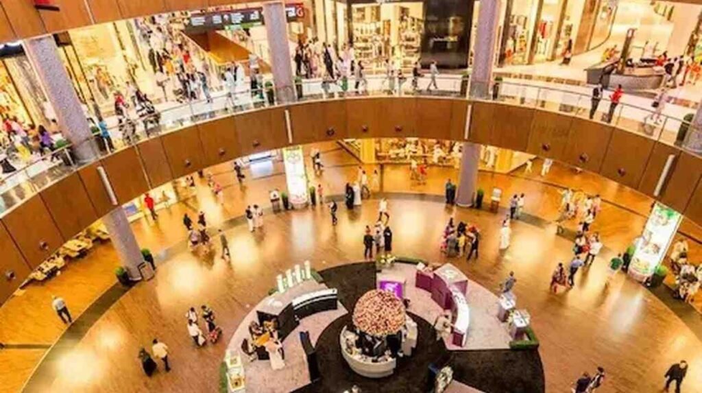 Shoppers walking through the spacious central atrium inside Mall of the Emirates, surrounded by luxury stores, multiple shopping levels and the bright open interior.