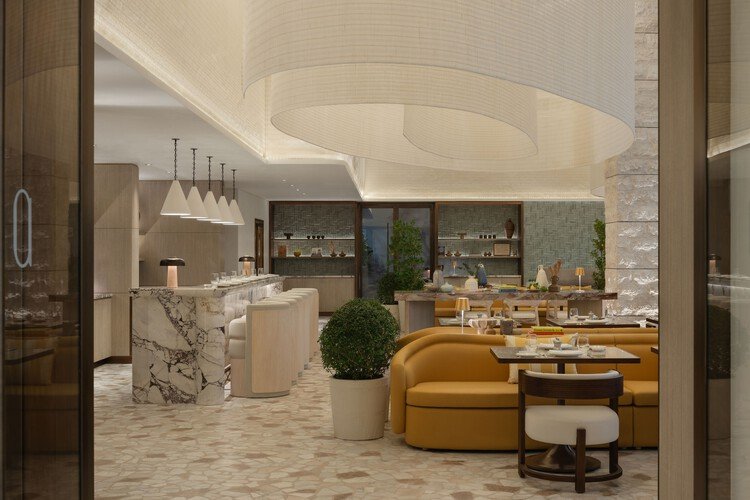 Elegant hotel lounge in Dubai featuring a marble bar, curved seating, warm lighting, natural stone finishes, and modern sustainable interior design.