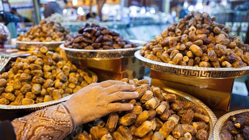 A visitor examines premium dates displayed in large traditional bowls at the Dubai Date Festival, highlighting local date varieties and Emirati agricultural heritage.