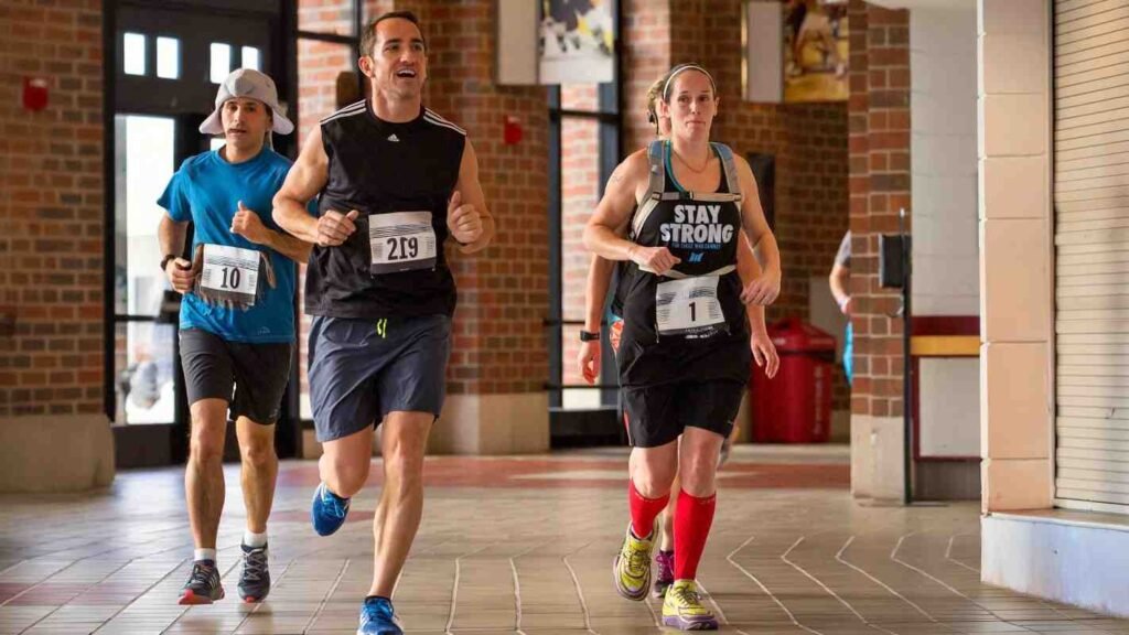 Participants taking part in an indoor running event at Dubai Outlet Mall with race numbers, live entertainment, and family activities.