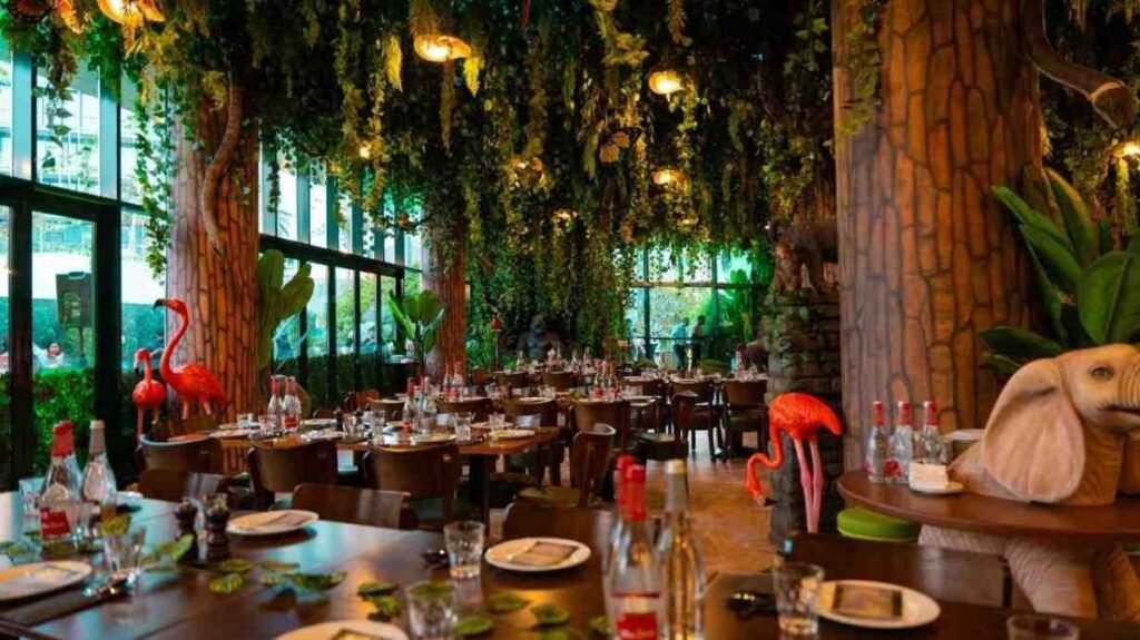 The rainforest themed dining area at JNGL inside The Green Planet Dubai, featuring tropical plants, hanging vines, and animal inspired decorations.