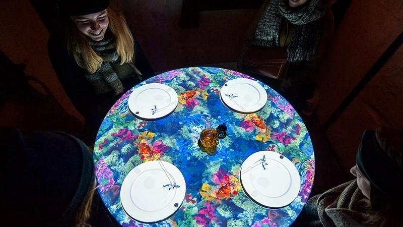 A colorful animated projection transforms the dining table at Le Petit Chef, creating an interactive culinary experience for guests.