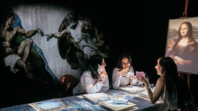 Guests enjoy the Seven Paintings dining experience as famous works of art are projected onto the walls and tables around them.